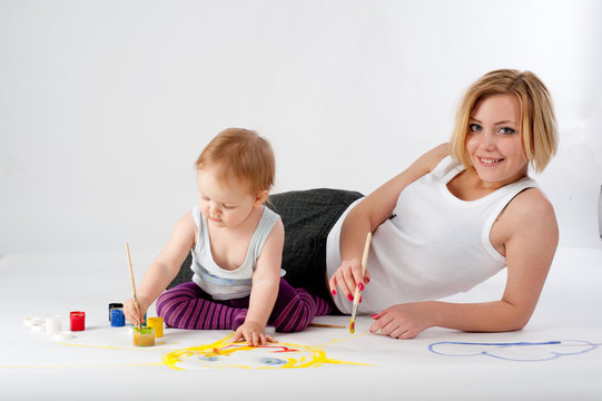 Pretty young mother and daughter drawing