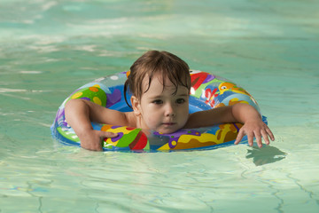 Ребенок учится плавать в крытом бассейне