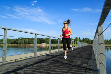 Woman running on a boardwalk at a lake.