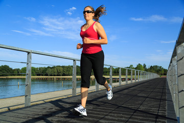 Healthy woman running on a boardwalk at a lake.