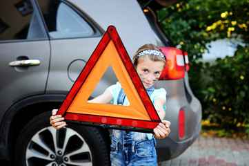 Unhappy kid girl holds red warning triangle