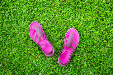 Top view of pink sandals on green grass.