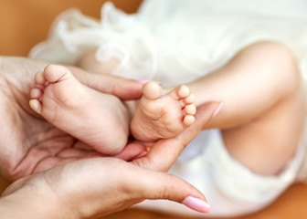 Fototapeta na wymiar Baby feet cupped into mothers hands.
