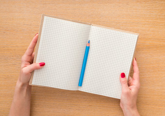 Women hand holding new notebook on wooden background