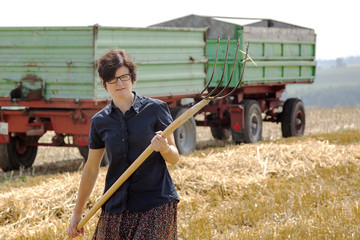 Women farmers with pitchfork works on the field
