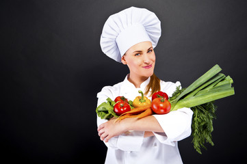 woman chef make hand heart sign with tomato over dark background