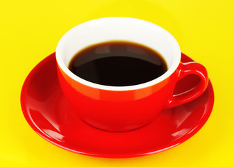 A red cup of strong coffee on yellow background