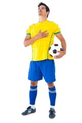 Football player in yellow with ball listening to anthem