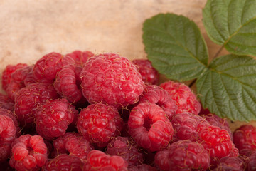 Few raspberries with leaf on wooden background