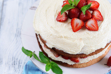 Delicious biscuit cake with strawberries on table close-up