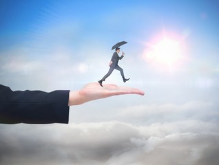 Composite image of businessman jumping holding an umbrella