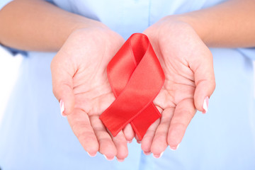 Woman with aids awareness red ribbon in hands isolated on white