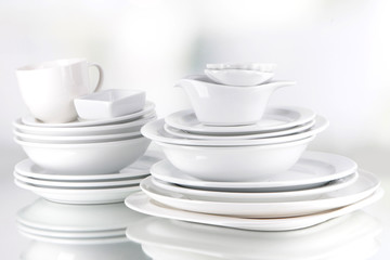 White crockery and kitchen utensils, on light background