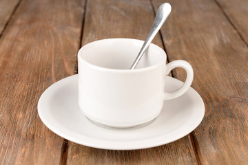 Empty cup with tea spoon on wooden background
