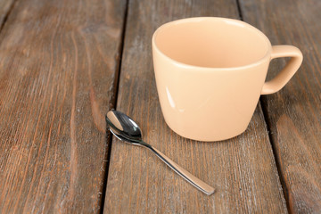 Empty cup with tea spoon on wooden background
