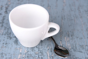 Empty cup with tea spoon on wooden background