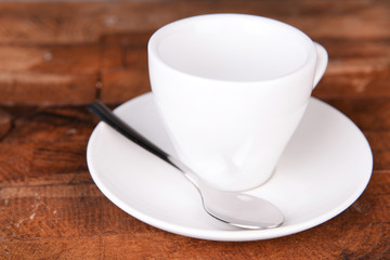 Empty cup with tea spoon on wooden background