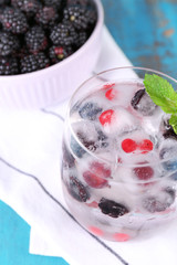Cold cocktail with forest berries, frozen in ice cubes and