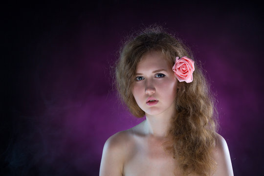 Studio portrait of young beautiful woman with roses in the smoke
