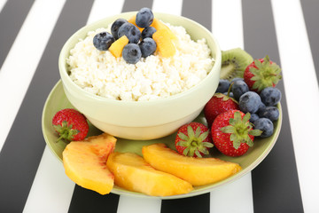Cottage cheese with fruits and berries in bowl on table