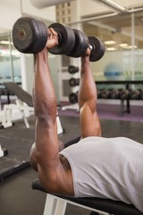 Fototapeta na wymiar Muscular man exercising with dumbbells