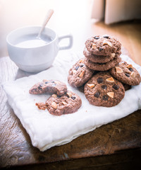 Chocolate chip cookies on napkin and hot tea on wooden table.