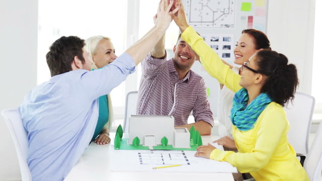 smiling architects doing high five in office