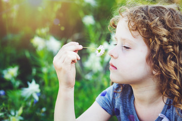 Curly baby with flowers in her hand. Toning photo.