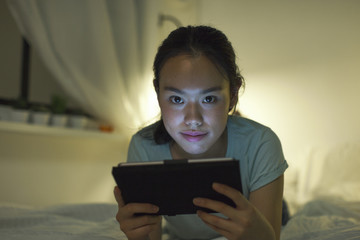 Naklejka premium Young asian woman lying on bed and using digital tablet.