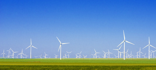 grüne wiese mit windkraftanlagen zur stromerzeugung