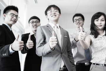 Business team holding their thumbs up