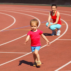 Mother & little daughter running around the stadium. 