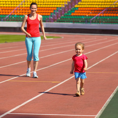 Mother & little daughter running around the stadium. 