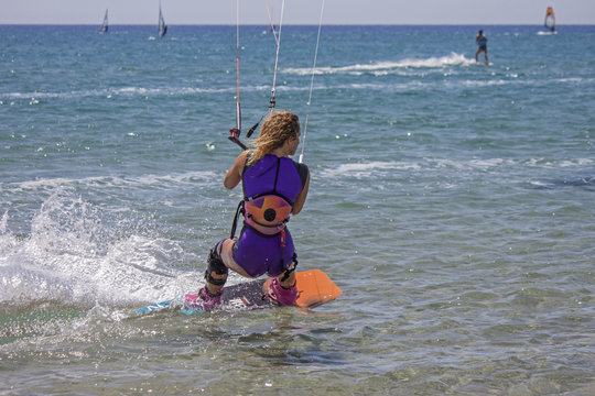 a young girl engaged in an acrobatic leap to kitesurf