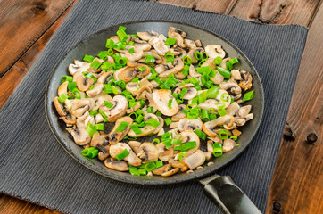 Fried mushrooms with spring onion on pan