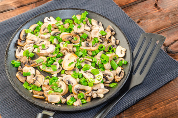 Fried mushrooms with spring onion on pan
