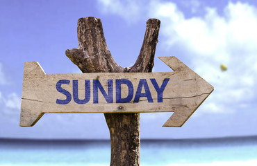 Sunday wooden sign with a beach on background