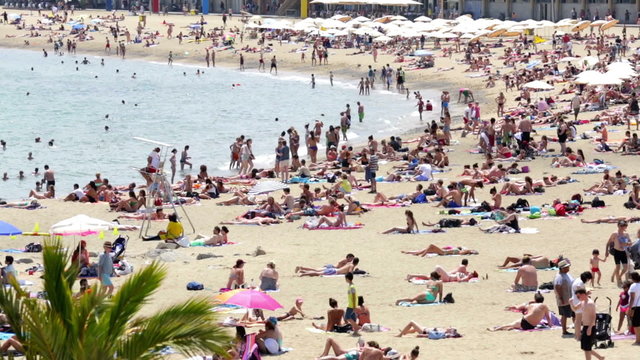 People sunbathing on sunny summer beach in Barcelona