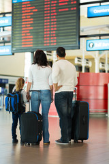 family checking flight information at airport