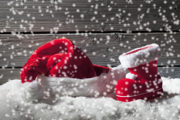 Nikolausmütze und Stiefel auf Schnee vor Holzhintergrund