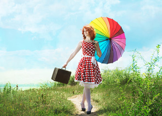 Retro style redheaded girl walking with a colorful umbrella