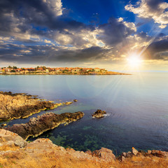 ancient city on a rocky shore near sea at sunset