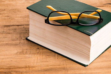 eyeglasses and books on wooden background