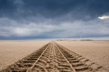 Tuinposter Tyre tracks on the sand of the beach © Noradoa
