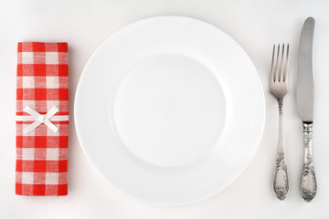 Vintage cutlery set with fork, knife, plate and red napkin.