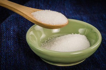 Sugar on wooden spoon on blue fabric