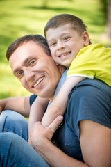 Obraz premium Smiling happy father and son hugging in the park