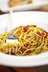 close up spaghetti and bacon fried in white dish