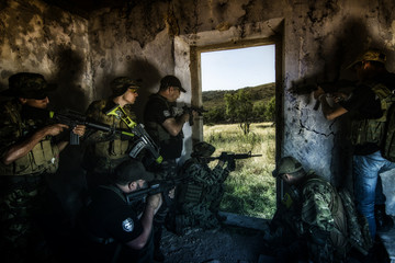 Airsoft group team in daytime action hiding