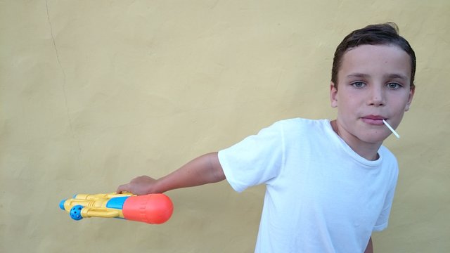 Ni&ntilde;o con piruleta y pistola de agua
